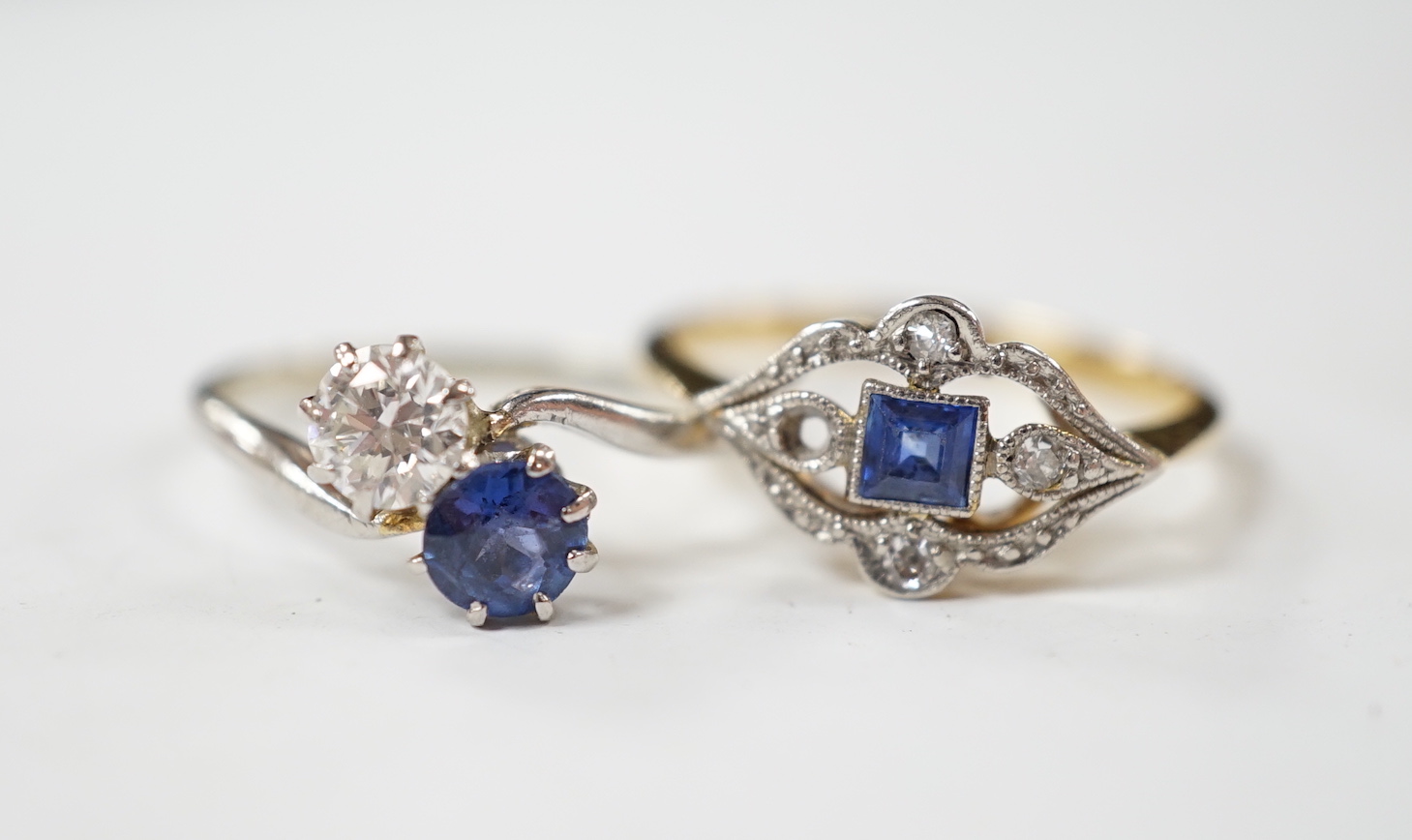 An early 20th century 18ct and plat, sapphire and diamond set cluster ring (stone missing), size N/O and a white metal, sapphire and diamond set two stone crossover ring, size M, gross weight 4.6 grams.